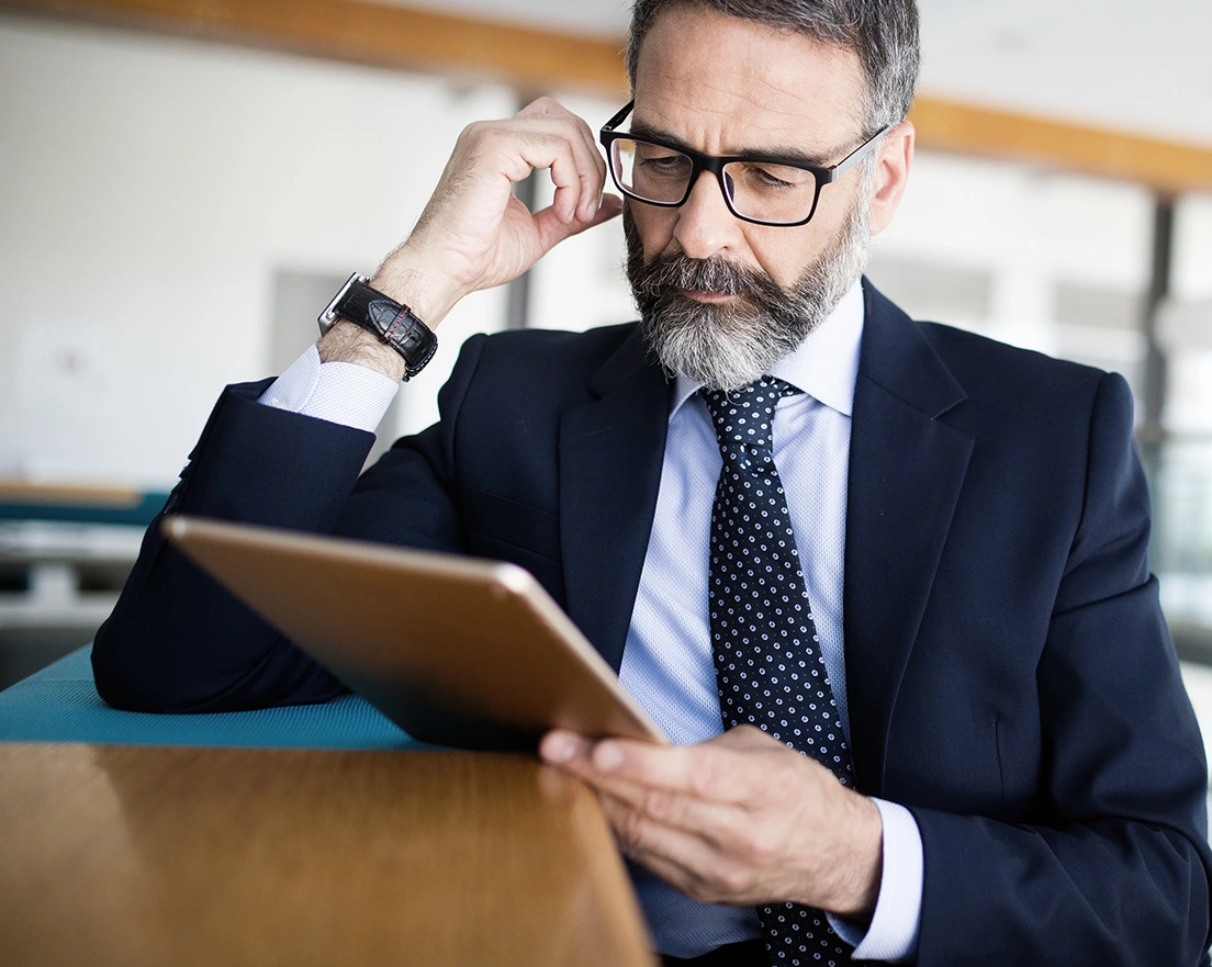 Distinguished man in a suit looking at a tablet